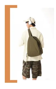 Back view of a man wearing a large olive green nylon sling bag for sports and fitness.