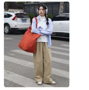 Detailansicht einer großen orangefarbenen Nylon-Stofftasche am Modell