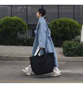Detail eines großen schwarzen Nylon-Tote-Bag, getragen von einem Modell auf der Straße