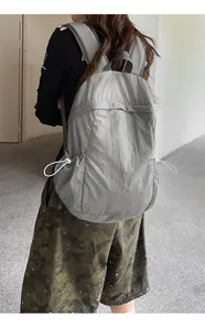 Detailed back view of a stylish grey lightweight minimalist backpack worn by a model