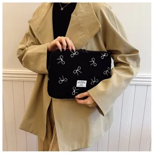 Detailweergave van pluche zwarte iPad-hoes met geborduurde strikpatronen door model