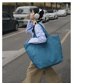 Große blaue Tragetasche aus Nylon mit Falten in einer Lifestyle-Straßenansicht