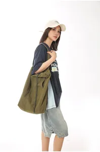 Detail view showing the large olive green nylon tote bag carried by an Asian model
