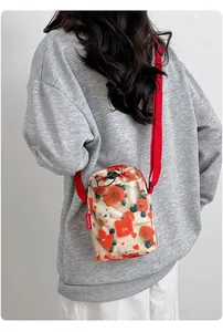 Detalle del estampado floral de rosas y ositos en un bolso bandolera de malla para móvil