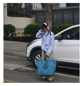 Straßenstil-Modell mit einer großen blauen Vintage-Nylon-Tragetasche im Freien