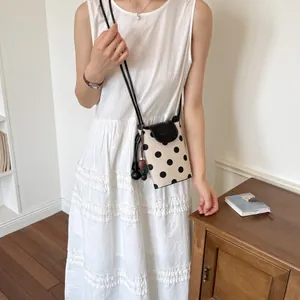 Detailed view of a chic polka dot crossbody phone bag with black flap and shoulder strap.