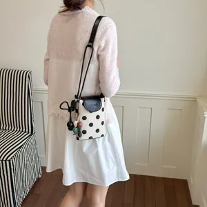 Canvas polka dot crossbody phone bag with black leather flap and shoulder strap for women.