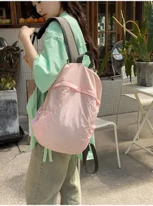 Detailed view of a lightweight pink travel backpack worn by a woman in an outdoor setting