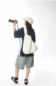 Minimalist beige nylon drawstring shoulder bag shown in a detailed lifestyle back view