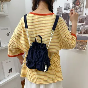 Dunkelblauer wasserdichter Nylon-Rucksack mit Kordelzug, am Modell für Reisen gezeigt.
