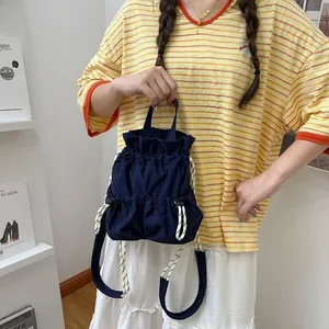Marineblauer Nylon-Kordelzug-Rucksack, von einem Model in minimalistischer Umgebung gehalten