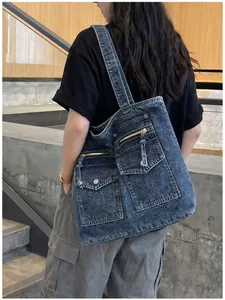 Rear view of model carrying a large denim tote bag with functional pockets.