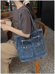 Detailed shot of a distressed denim tote bag worn over the shoulder by a model