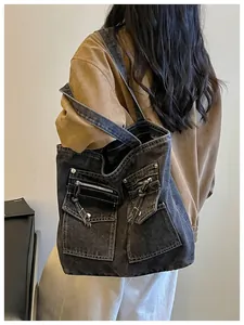 Detailed back view of a large black washed denim tote bag with functional pockets.