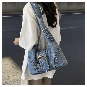 Close-up of vintage denim shoulder bag with heavy silver metal buckle and rivets.