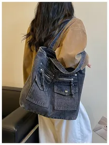 Detailed back view of a large washed black denim tote bag with multi-pockets on a model