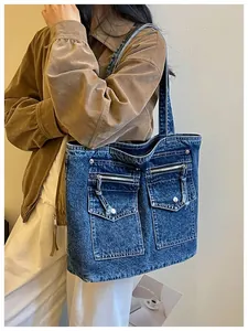 Model wearing a stylish blue denim tote bag with functional front pocket details