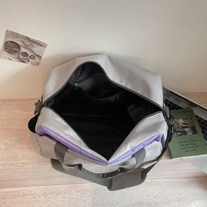 Grand sac de sport gris avec touches violettes, ouvert pour le voyage ou le fitness
