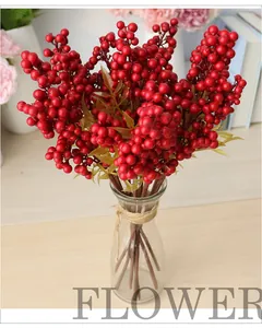 Künstliche rote Beerenstiele in einer Glasvase für die Weihnachtsdekoration.