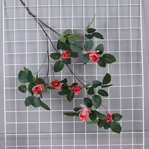 Vista dettagliada de una rama de rosa artificial colgada en un panel de rejilla blanca