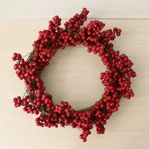 Détail d'une couronne de Noël festive avec des baies rouges vibrantes et une base en vigne.