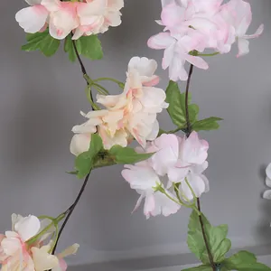 Gros plan de pétales de cerisier artificiels rose clair et de feuilles de soie.