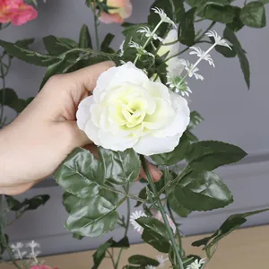 Close-up detail of a white artificial rose vine with realistic silk petals and leaves