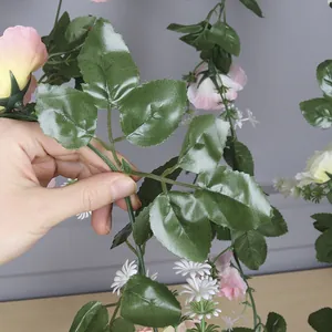 Close-up of green leaves and delicate pink rose buds on an artificial vine