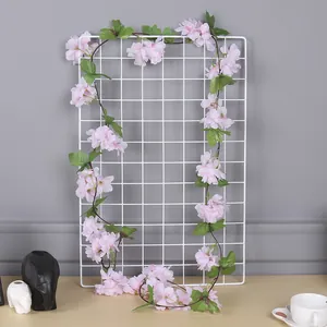 Détail d'une vigne de fleurs de cerisier artificielles roses sur une grille pour la maison