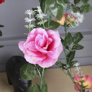 Detailed close-up view of a blooming pink artificial rose on a green vine stem