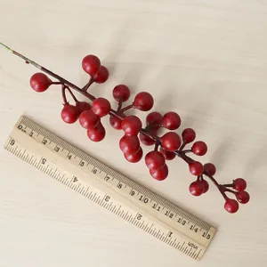 Tige de baies rouges artificielles à côté d'une règle en bois mesurant 15 cm