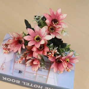 Close-up of pink artificial daisy bouquet with green leaves on a book