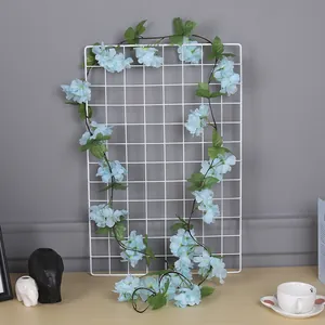 Longue guirlande de fleurs de cerisier bleues artificielles sur une grille décorative.