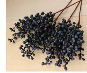 Detailed close-up of dark blue artificial berry branches with five stems on wood.