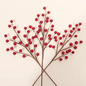 Vue détaillée de baies de houx rouges artificielles sur des branches pour Noël.
