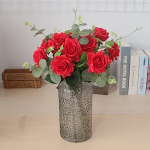 Roses rouges artificielles réalistes avec eucalyptus dans un vase en verre gris décoratif.