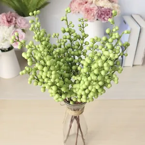 Decorative lifelike green artificial berry branches displayed in a clear glass vase for home