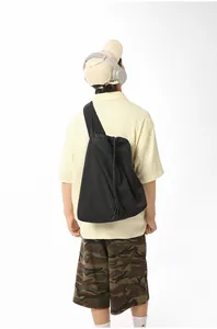 Back view of a man carrying a large black nylon sports tote bag in a minimalist style.