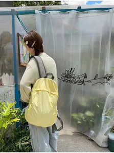 Female model wearing a minimalist yellow lightweight backpack outdoors for daily travel.