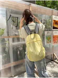 Lightweight yellow minimalist backpack for travel and daily commute shown on model.