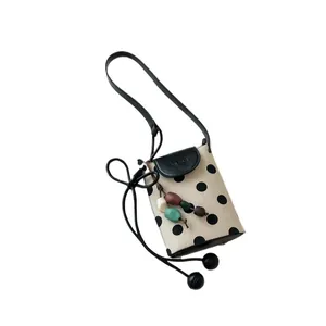 Stylish beige polka dot crossbody phone bag with black flap and decorative beads for women.