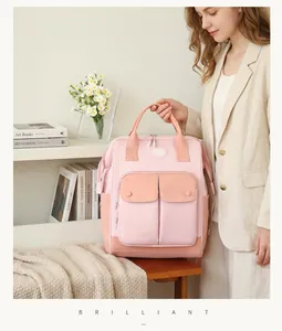 Close-up of pink multi-functional diaper bag with large front pockets held by model
