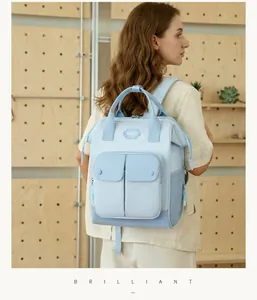 Back view of a stylish light blue large capacity diaper backpack worn by a model indoors