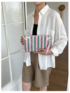 Lifestyle view of a pink and green striped travel makeup bag with wristlet strap