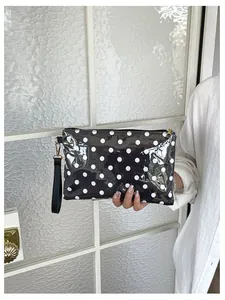Detailed view of the black and white polka dot travel cosmetic bag with wristlet strap.