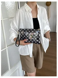 Woman holding a black and white polka dot makeup clutch bag for travel organization