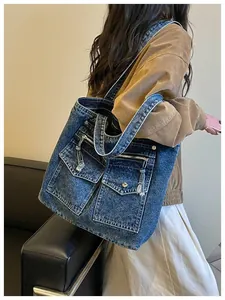 Model wearing a large capacity blue denim tote bag with functional front pockets.