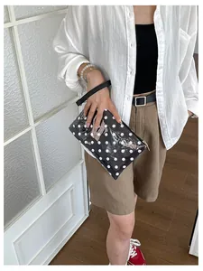 Detailed view of a black and white polka dot travel cosmetic bag with a hand strap