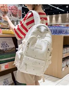Una chica lleva una mochila escolar blanca grande con patrones de osos en una tienda