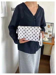 Detail of a white waterproof polka dot cosmetic bag with a wrist strap held by a model